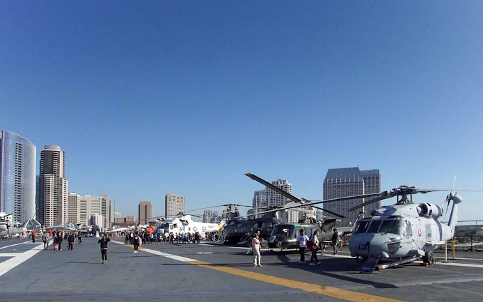 USS Midway Museum flight deck with helicopters and city skyline in San Diego.