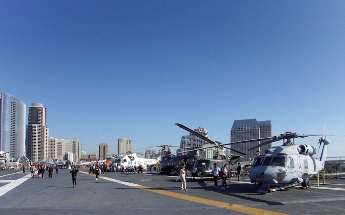 USS Midway Museum flight deck with helicopters and city skyline in San Diego.