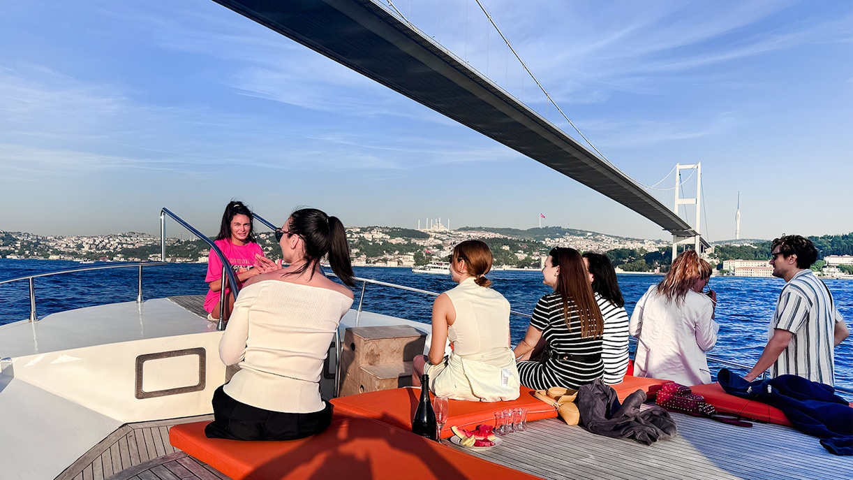 Passengers on a yacht viewing the Bosphorus Bridge in Istanbul.