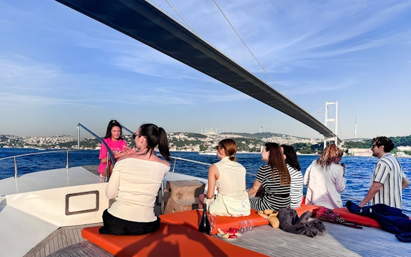 Passengers on a yacht viewing the Bosphorus Bridge in Istanbul.