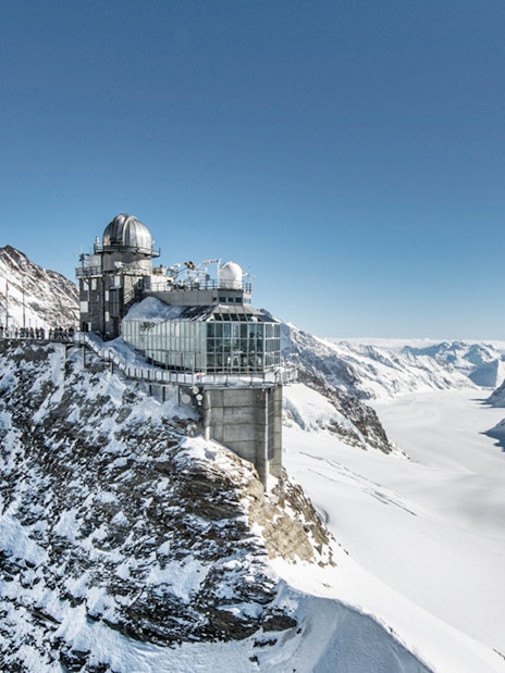 Sphinx Observatory perched on snowy peak at Jungfraujoch, surrounded by Swiss Alps.