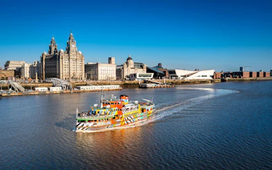 Colorful Mersey Ferry on River Mersey with Liverpool skyline in the background.