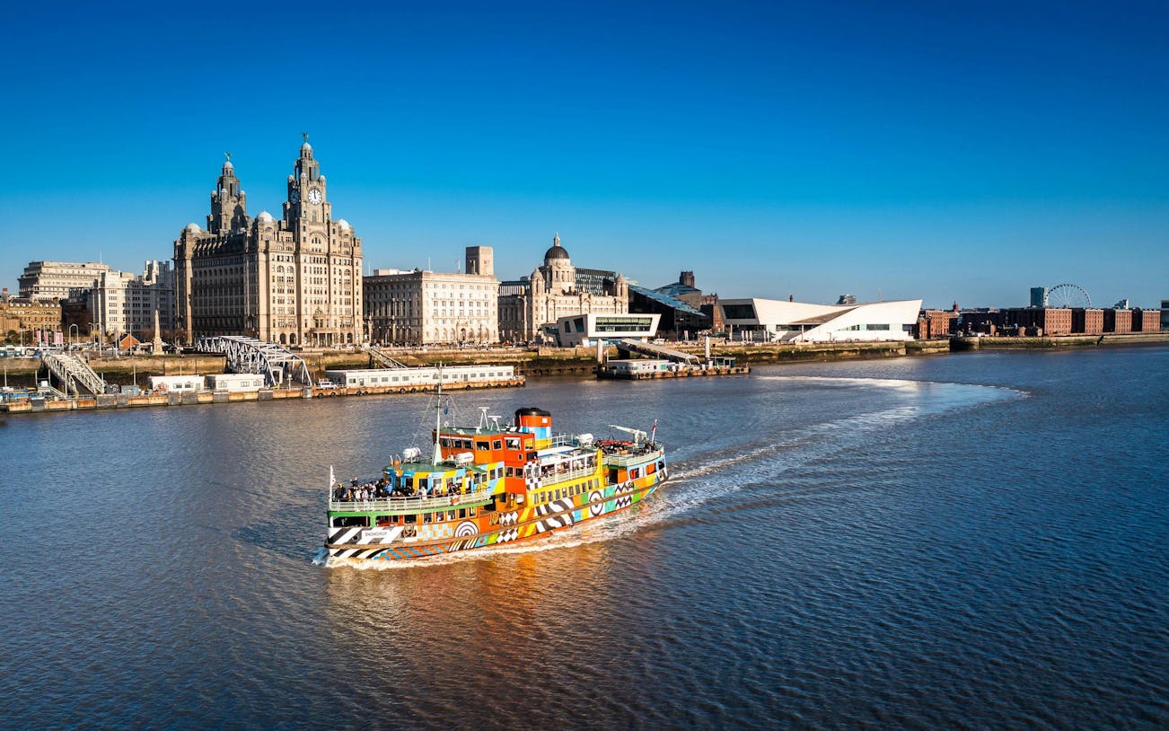 Colorful Mersey Ferry on River Mersey with Liverpool skyline in the background.