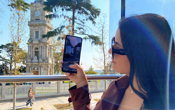 Woman on Istanbul hop-on-hop-off bus taking photo of Dolmabahçe Clock Tower.