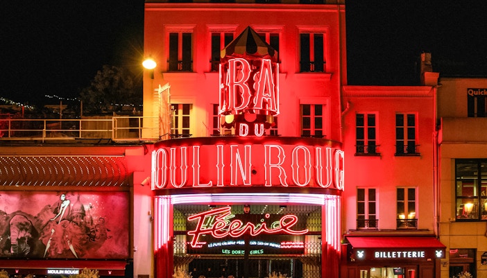 Moulin Rouge illuminated exterior at night in Paris, France.