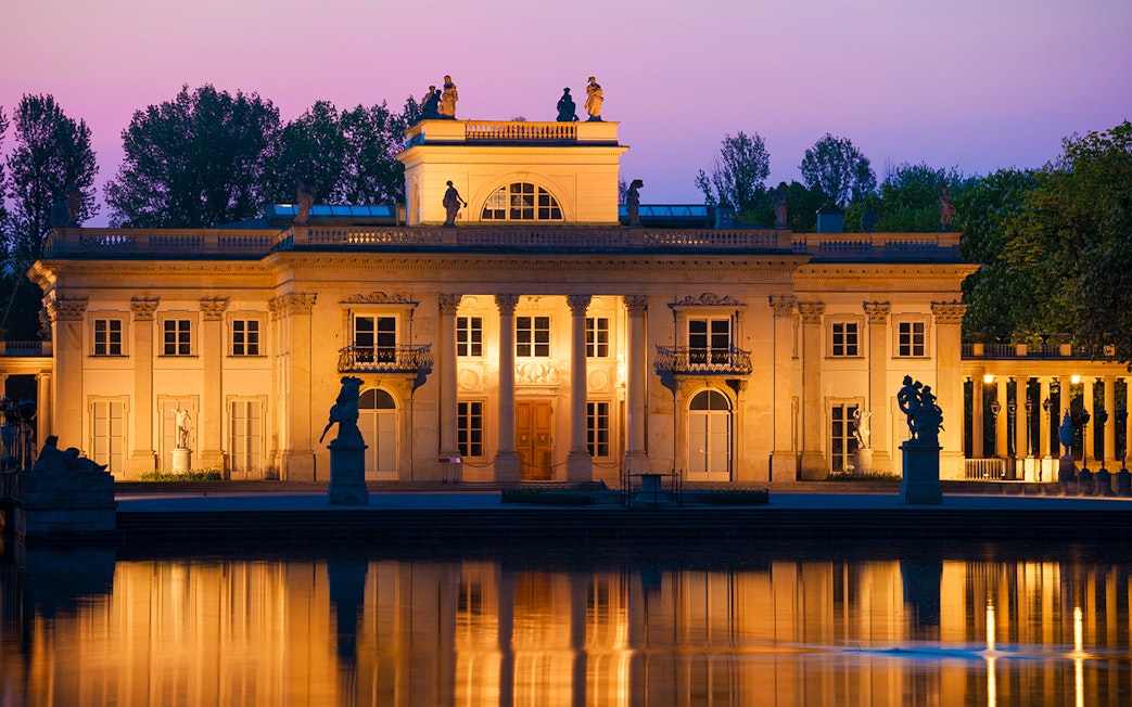 Lazienki Palace in Warsaw at sunset reflecting on the water.