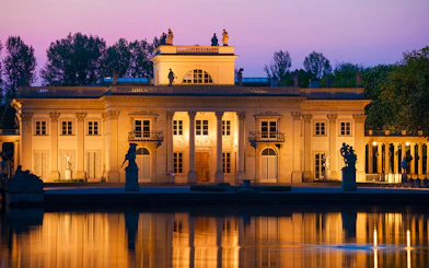 Lazienki Palace in Warsaw at sunset reflecting on the water.