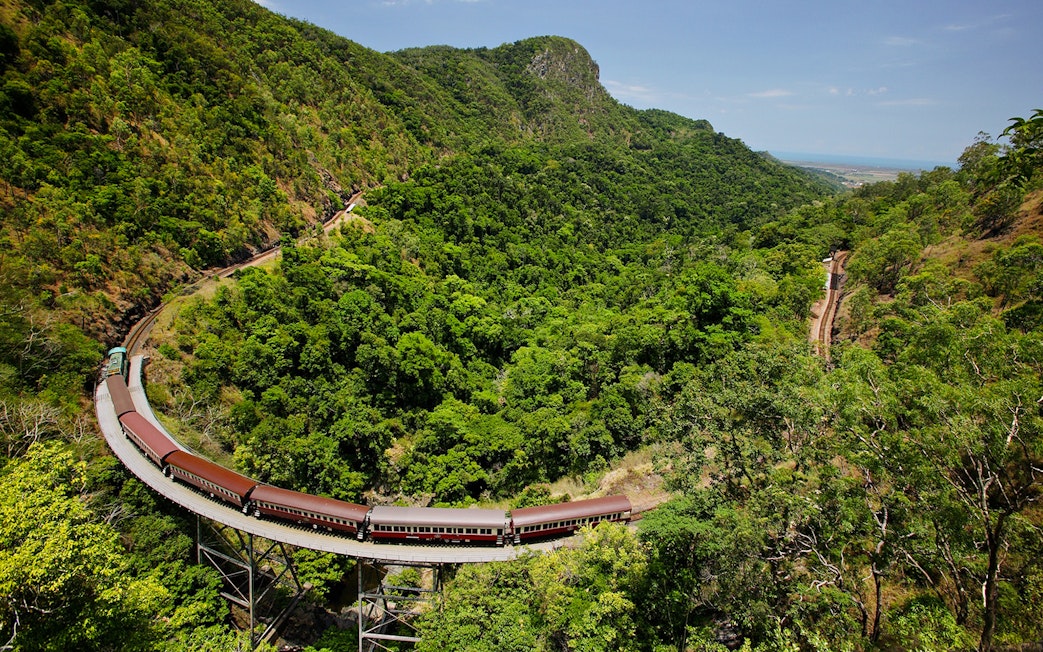 Aerial view of Kuranda Scenic Railway winding through lush green rainforest.