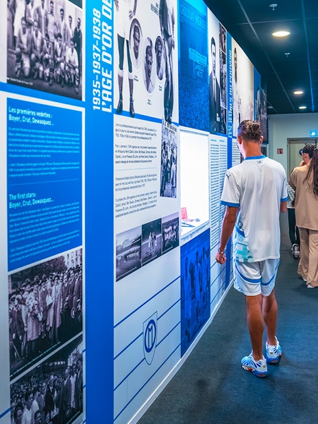 Visitors exploring the history wall during the OM Stadium tour.