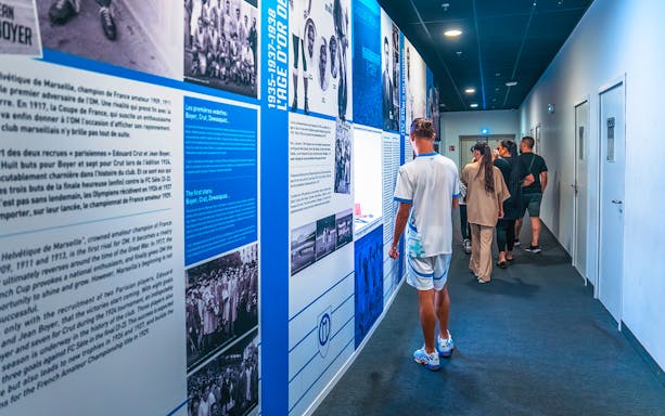 Visitors exploring the history wall during the OM Stadium tour.