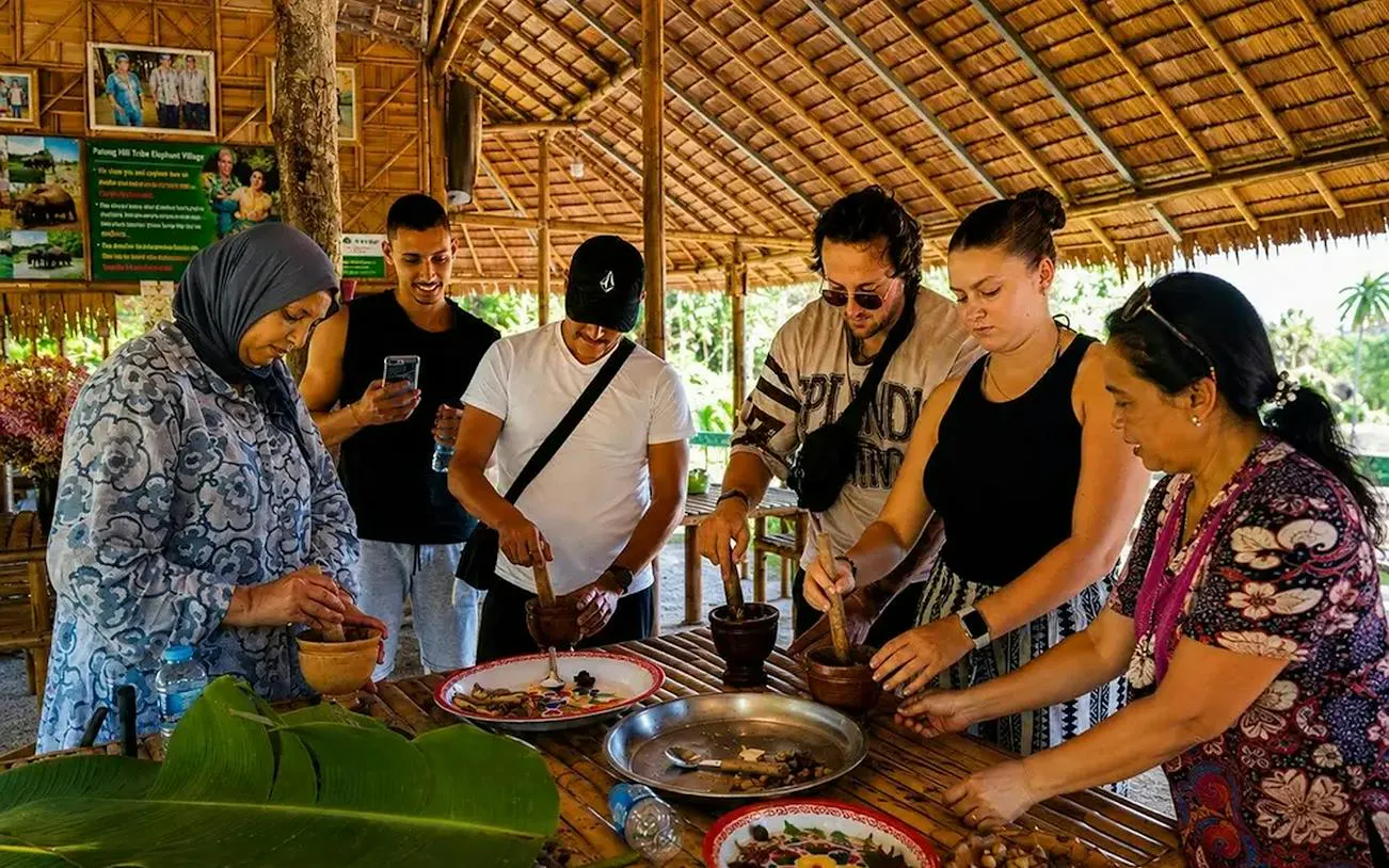 Tourists learning traditional cooking at an ethical elephant experience in Phuket.