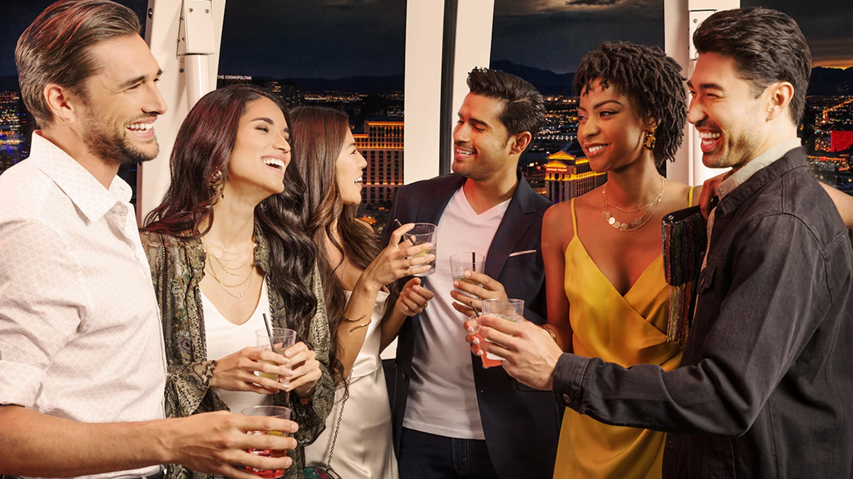 Group enjoying drinks on The High Roller at The LINQ with Las Vegas skyline in the background.