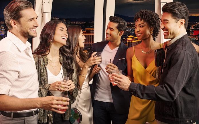 Group enjoying drinks on The High Roller at The LINQ with Las Vegas skyline in the background.