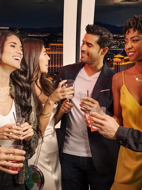Group enjoying drinks on The High Roller at The LINQ with Las Vegas skyline in the background.