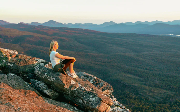 Person sitting on rock overlooking Grampians National Park during 1-day guided tour from Melbourne.