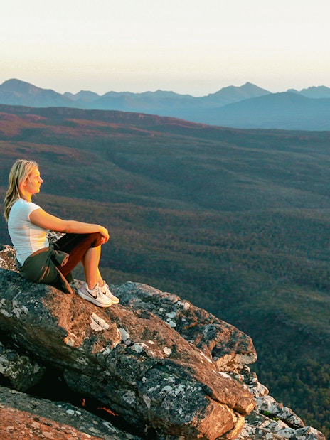 Person sitting on rock overlooking Grampians National Park during 1-day guided tour from Melbourne.
