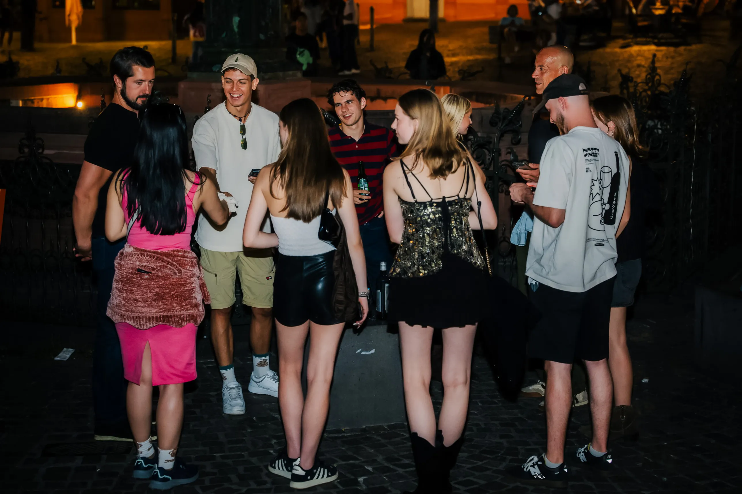 Group enjoying Frankfurt nightlife tour with drinks and socializing at an outdoor venue.