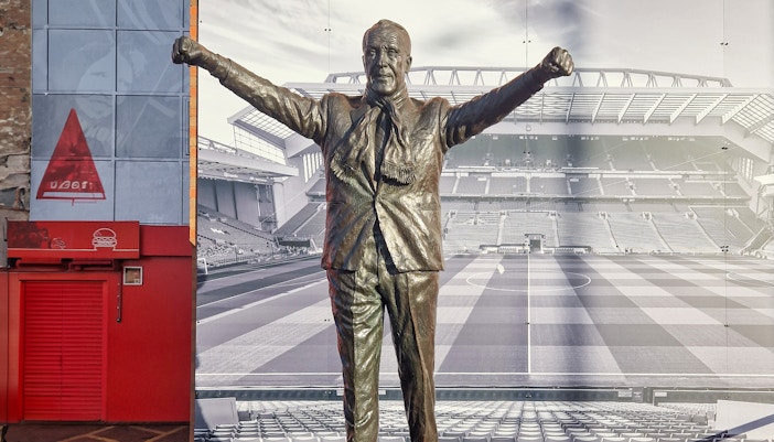 Liverpool FC stadium tour with view of Anfield pitch and iconic red seats.