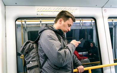 Man using phone on Copenhagen metro with city map above.