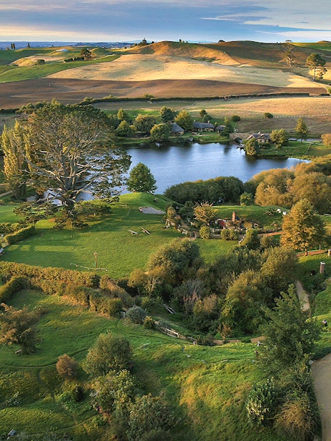 Hobbiton Movie Set with lush green hills and round doors, New Zealand.