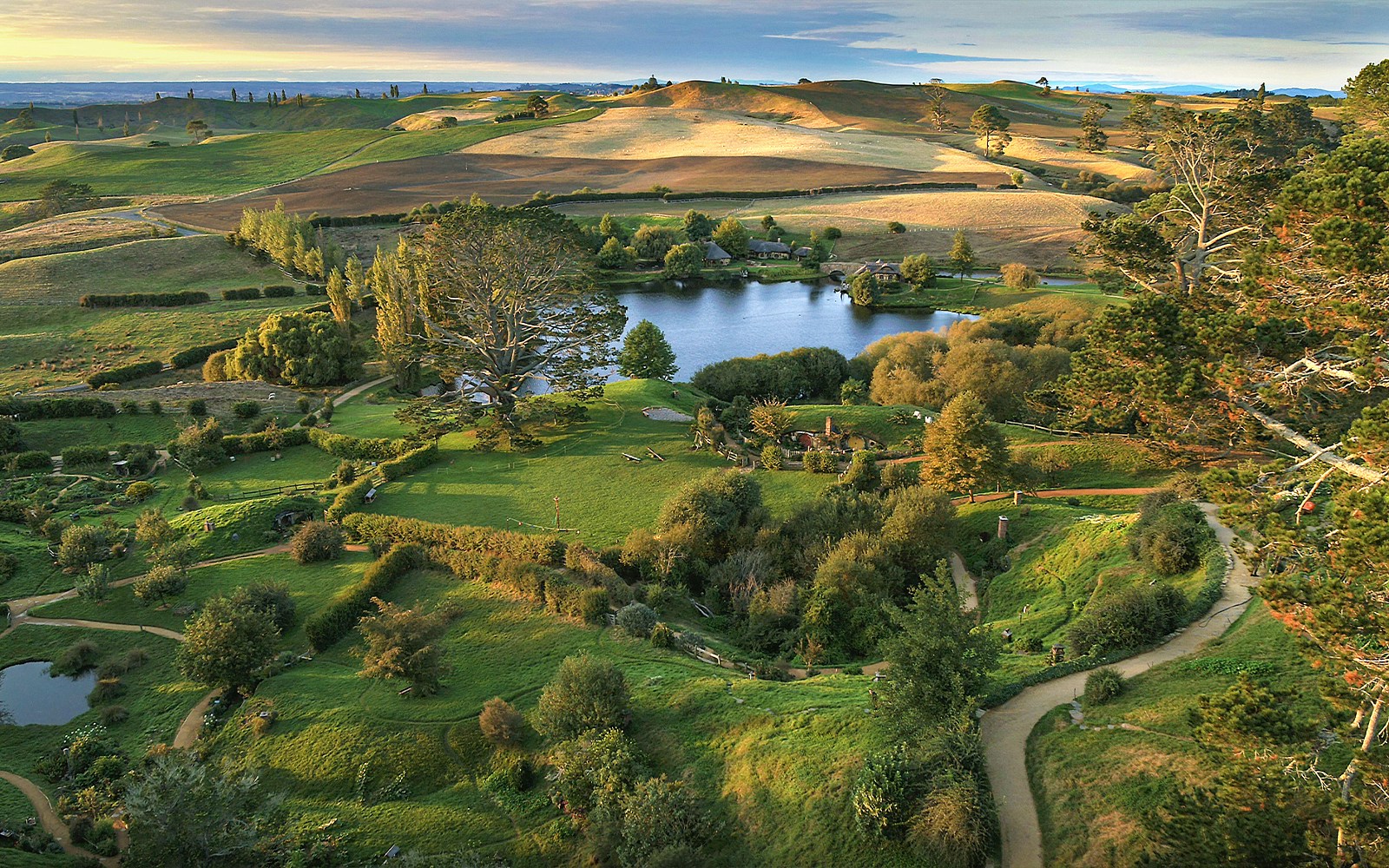 Hobbiton Movie Set with lush green hills and round doors, New Zealand.