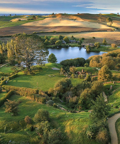 Hobbiton Movie Set with lush green hills and round doors, New Zealand.