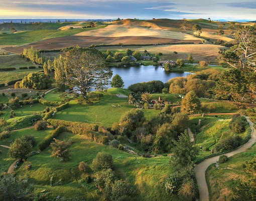 Hobbiton Movie Set with lush green hills and round doors, New Zealand.