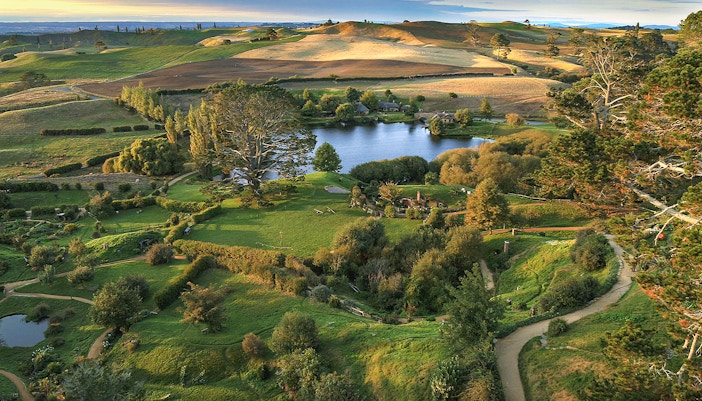 Hobbiton Movie Set with lush green hills and round doors, New Zealand.