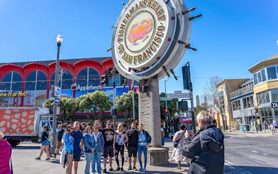Tourist photographing group near Fisherman’s Wharf sign, San Francisco.