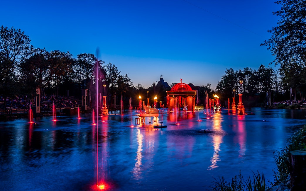 Evening fountain show with red lights at Puy du Fou, France.