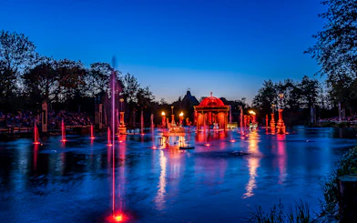 Evening fountain show with red lights at Puy du Fou, France.