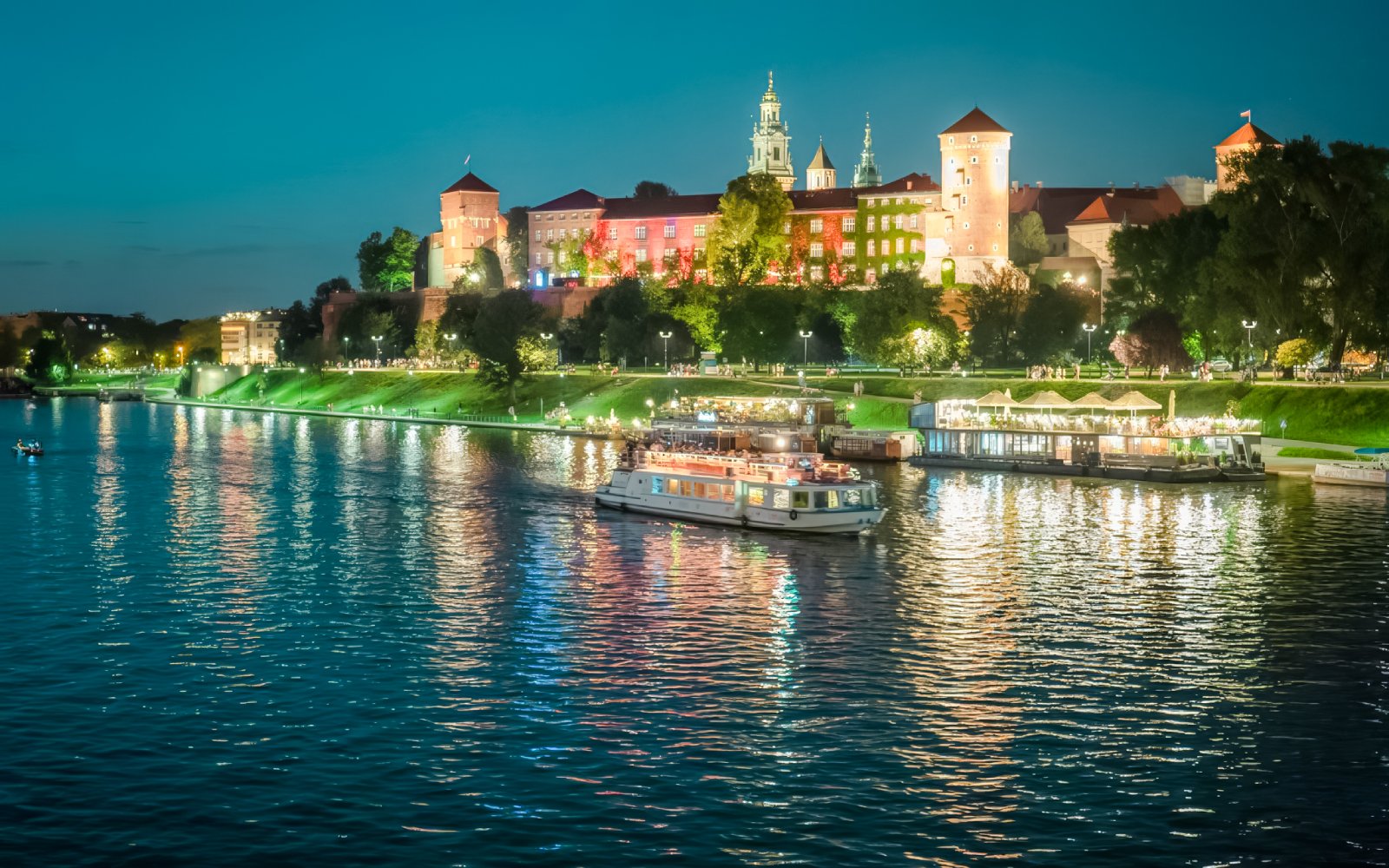 Night cruise on Vistula River with Wawel Royal Castle illuminated in the background, Krakow.
