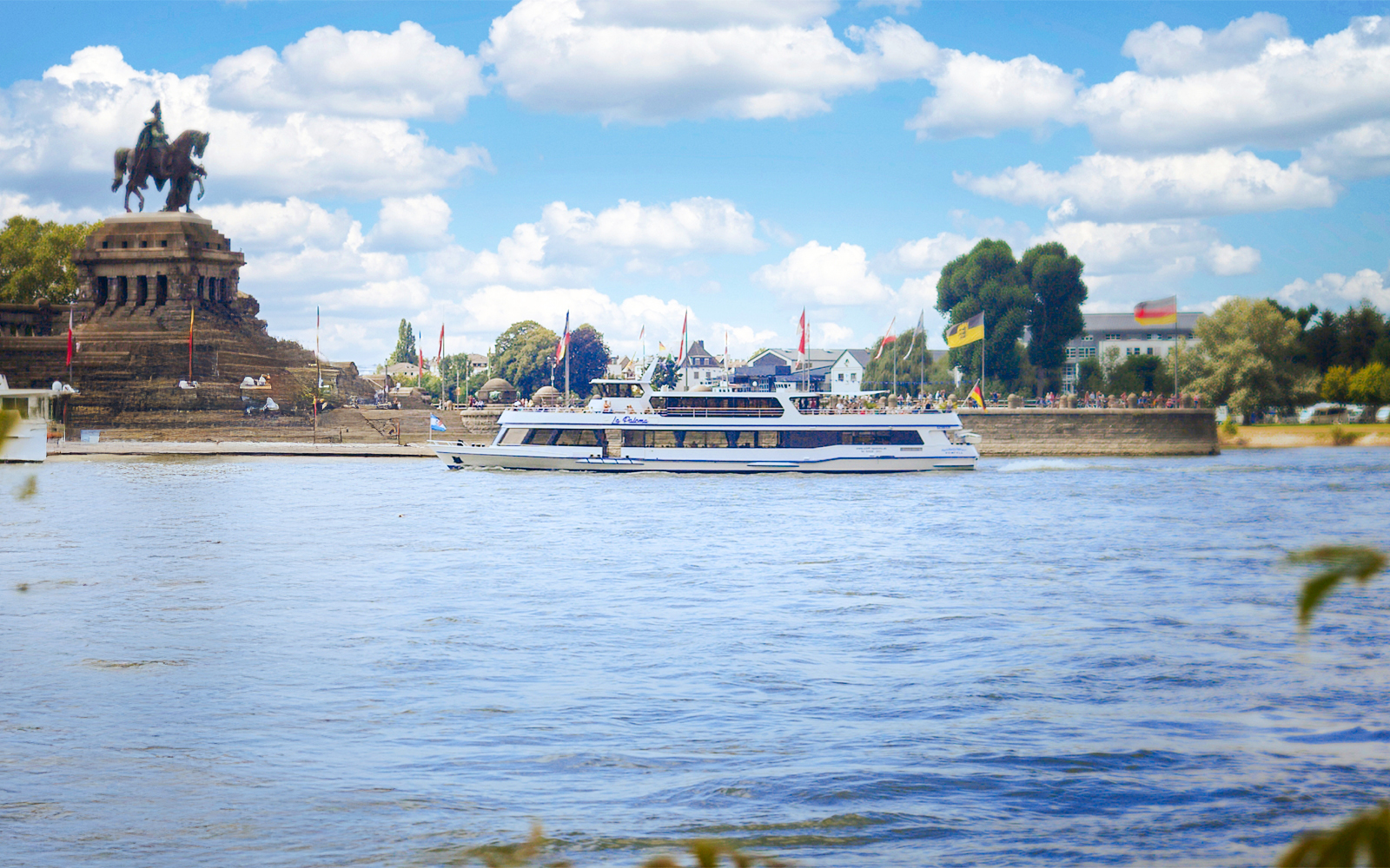 Koblenz sightseeing cruise passing Deutsches Eck monument on the Rhine River.