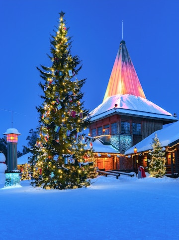Christmas tree and illuminated building at Santa Claus Village, Rovaniemi, Finland.