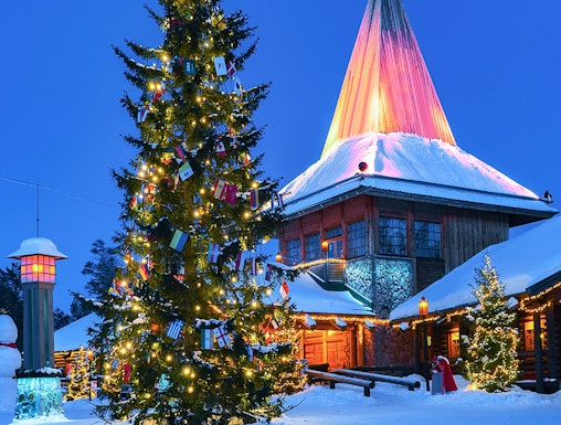 Christmas tree and illuminated building at Santa Claus Village, Rovaniemi, Finland.