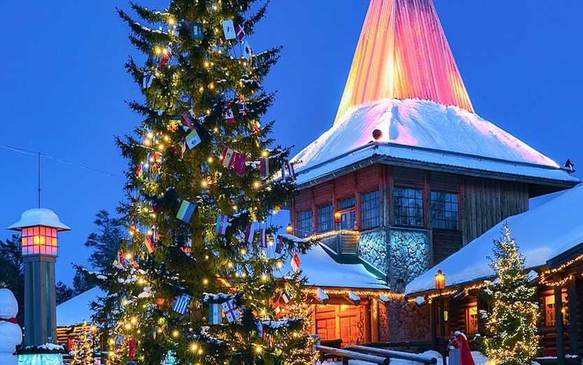 Christmas tree and illuminated building at Santa Claus Village, Rovaniemi, Finland.