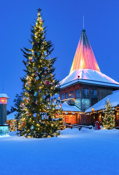 Christmas tree and illuminated building at Santa Claus Village, Rovaniemi, Finland.