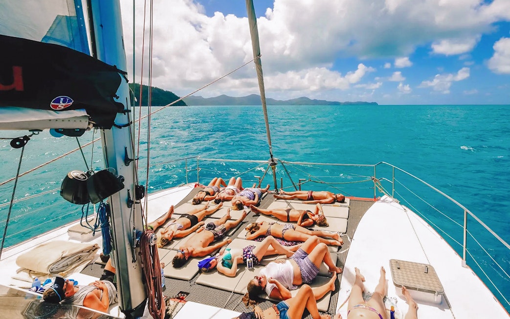 Tourists sunbathing on a sailboat deck in the Whitsundays.