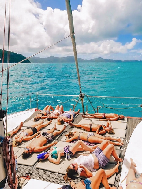 Tourists sunbathing on a sailboat deck in the Whitsundays.
