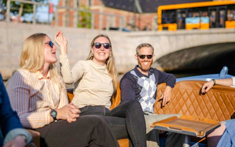 Guests smiling on a guided boat tour in Copenhagen, passing under a bridge.
