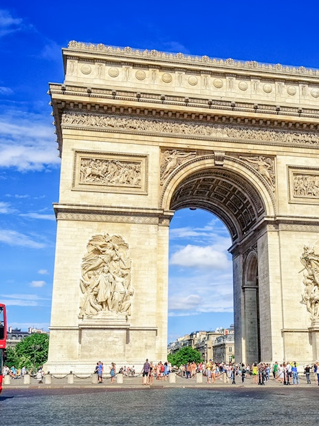 Arc de Triomphe with a red tour bus in Paris, part of the Paris in a Day Guided Tour.
