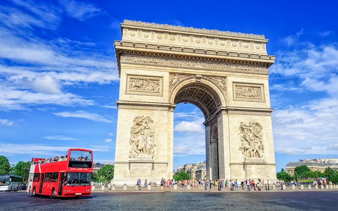 Arc de Triomphe with a red tour bus in Paris, part of the Paris in a Day Guided Tour.