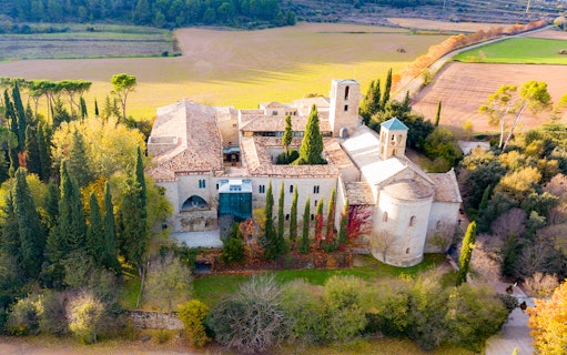Aerial view of Món Sant Benet monastery surrounded by lush countryside, highlighting medieval architecture.
