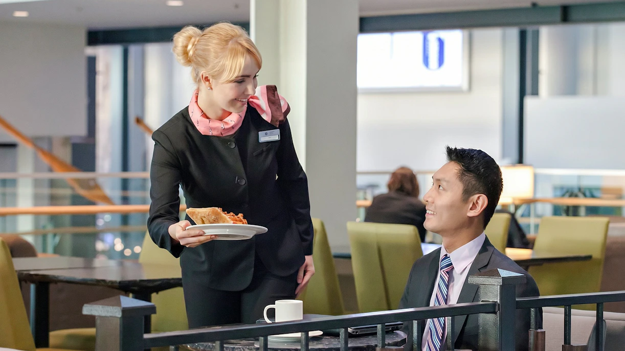 Server offering food to a guest at Plaza Premium Lounge, Vancouver International Airport.