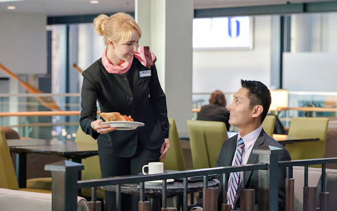 Server offering food to a guest at Plaza Premium Lounge, Vancouver International Airport.