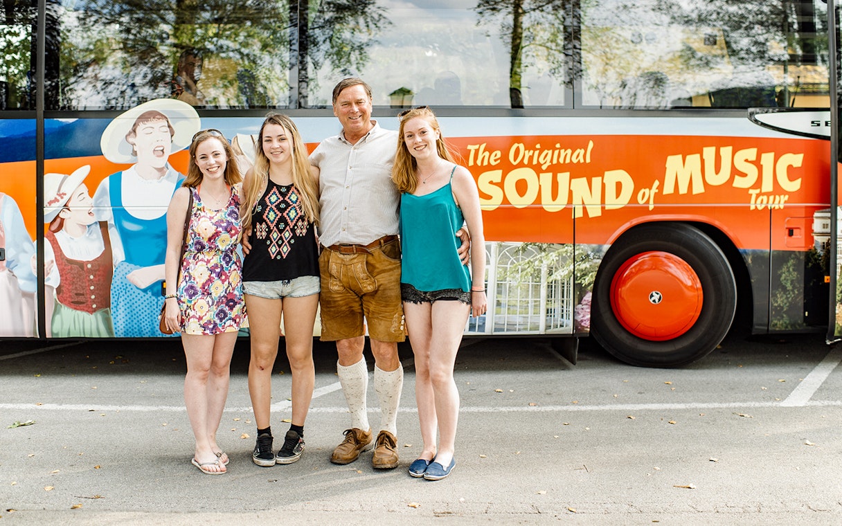 Tourists posing in front of the Original Sound of Music tour bus in Salzburg.
