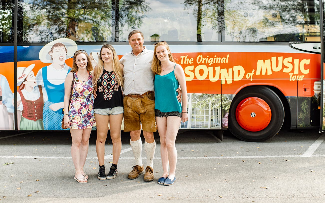 Tourists posing in front of the Original Sound of Music tour bus in Salzburg.