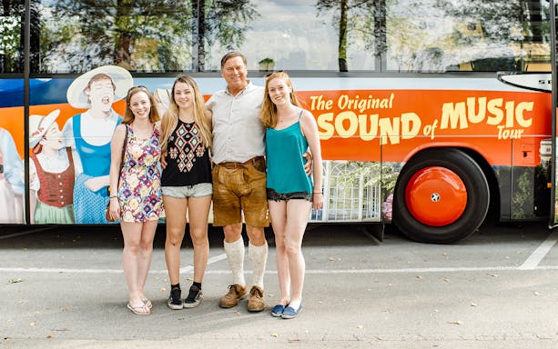 Tourists posing in front of the Original Sound of Music tour bus in Salzburg.