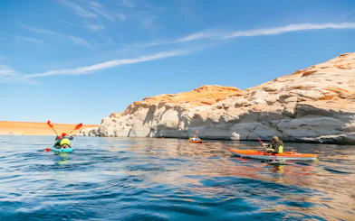 Kayakers paddling on Lake Powell near Antelope Canyon's sandstone cliffs.