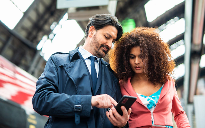 Travelers checking train schedule on phone at Firenze Santa Maria Novella Station.